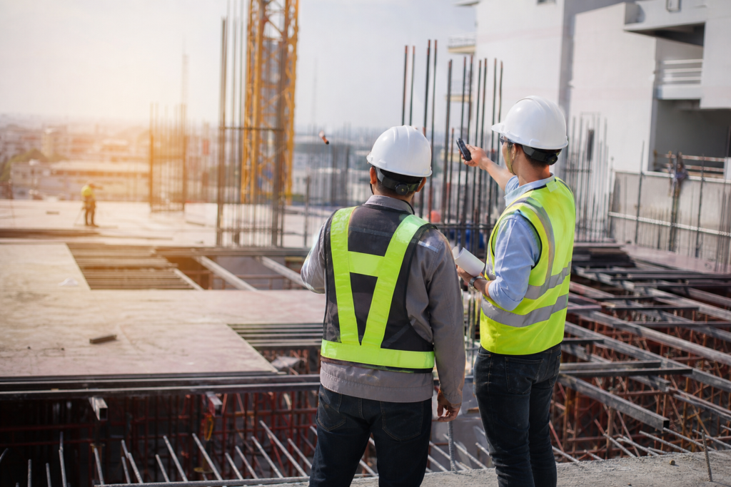 two field engineers in hard hats on a construction site discussing plans, reflecting field engineer recruitment trends